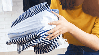 folded striped shirts being held by woman